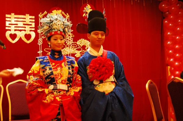Traditional Chinese wedding ceremony, with a double happiness character in the background. (Image: Hanfu Love via flickr CC BY 2.0 )