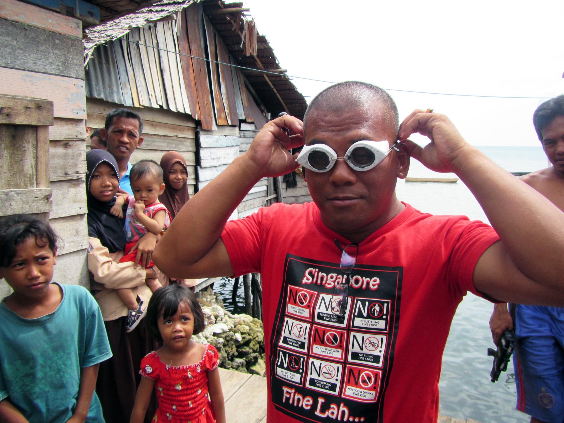 A Bajau villager demonstrates the use of traditional wooden goggles. (Photo by Melissa Ilardo)