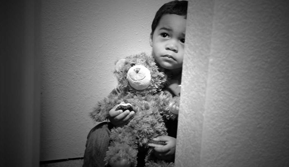 A freightened child holding a teddy bear.
