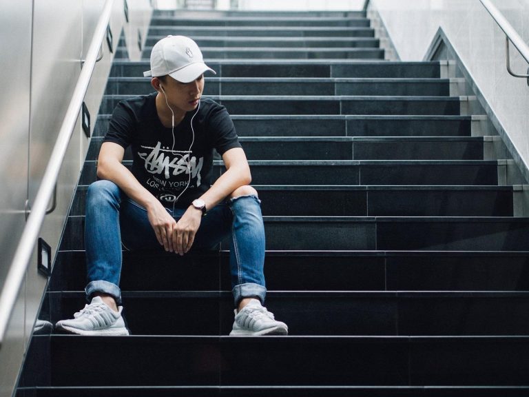 A young man sitting alone listening to music.