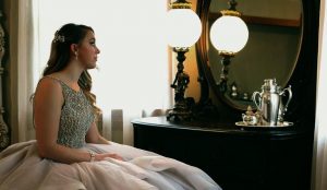 A woman in a dress looking in a mirror.