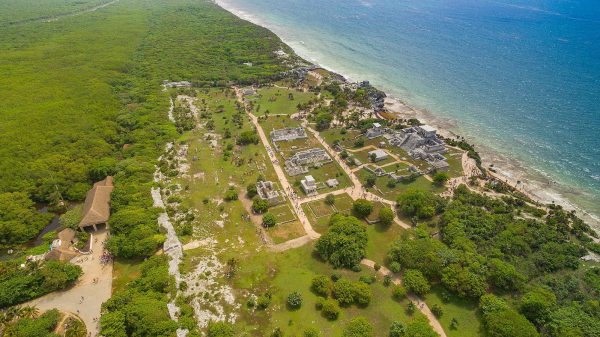 Ruins of tulum, ocean water, sand beach and green pastures