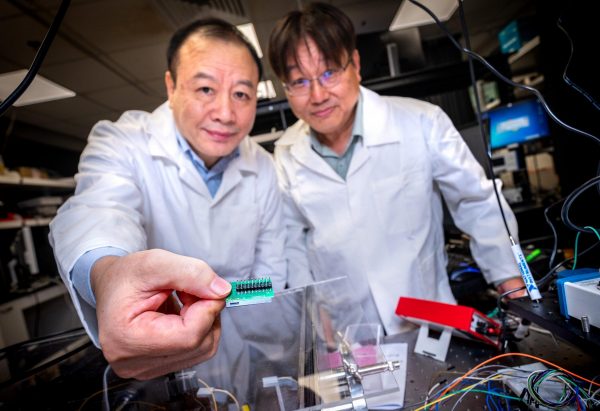 (L-R) NTU Prof Liu Ai Qun and Assoc Prof Kwek Leong Chuan showing the tiny 3mm quantum communication chip embedded on the bottom right of the green circuit board, which is 1,000 times smaller than current setups and provides almost unhackable levels of encryption. (Image: NTU Singapore)