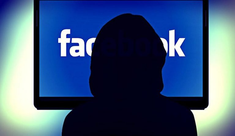 A silhouette in front of a screen with Facebook.