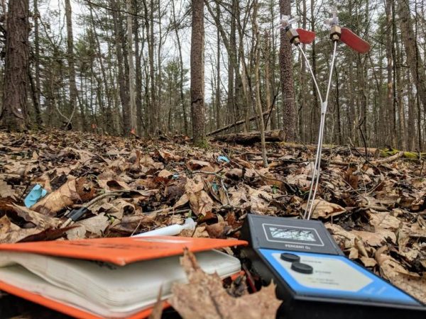 A soil oxygen meter and field book for recording soil oxygen concentrations in the Shale Hills watershed. In the background are soil gas wells for sampling 8-inch and 16-inch soil depths. (Image: CAITLIN HODGES)