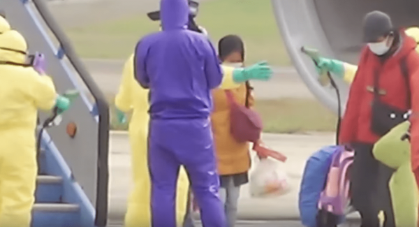 Officers at Indonesia's Batam airport spray passengers with disinfectant as they get off a plane arriving from Wuhan. They were later transferred on a flight to Natuna Island where they are being quarantined for two weeks. (Image: YouTube/Screenshot)