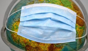 A face mask on a world globe.