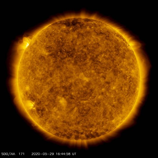 On the upper left side of this image from May 29, 2020, from NASA's Solar Dynamics Observatory — shown here in the 171-angstrom wavelength, which is typically colorized in gold — one can see a spot of light hovering above the left horizon. This light emanates from solar material tracing out magnetic field lines that are hovering over a set of sunspots about to rotate over the left limb of the Sun. (Image: NASA/Solar Dynamics Observatory/Joy Ng)