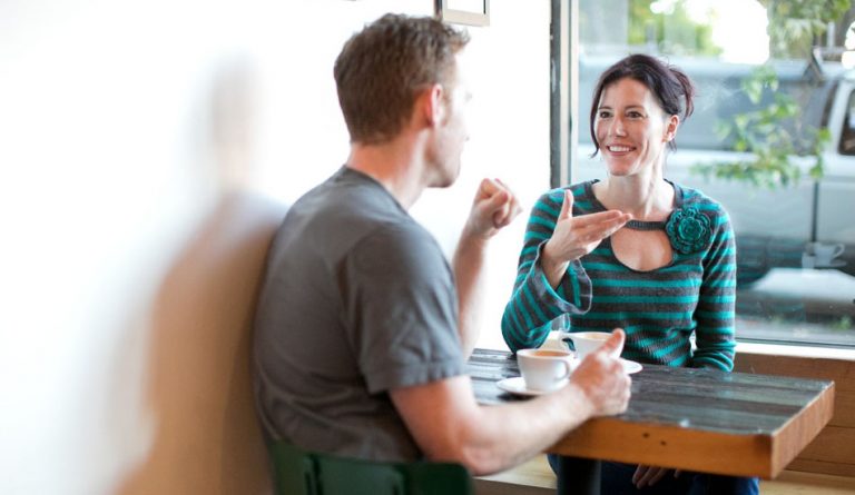 Smiling couple talking at a table.