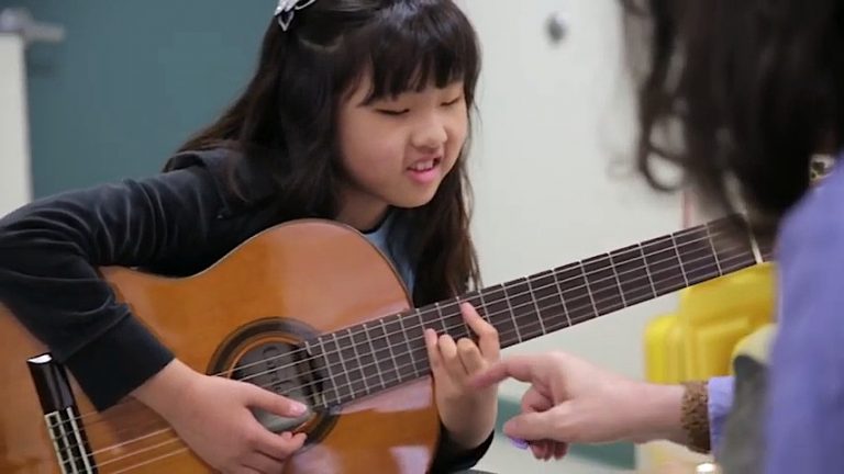 A blind girl learning to play the guitar.