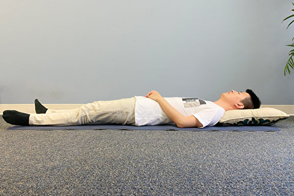 A man sleeping on his back with hands resting on the abdomen.