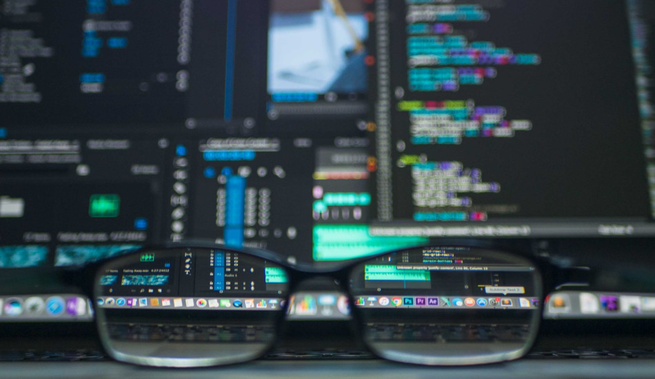 A pair of glasses sitting in front of a computer monitor.