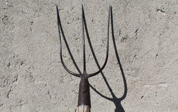 A pitchfork leaning against a wall.