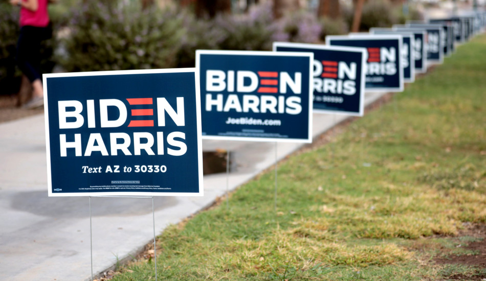 Signs for Joe Biden line a sidewalk.