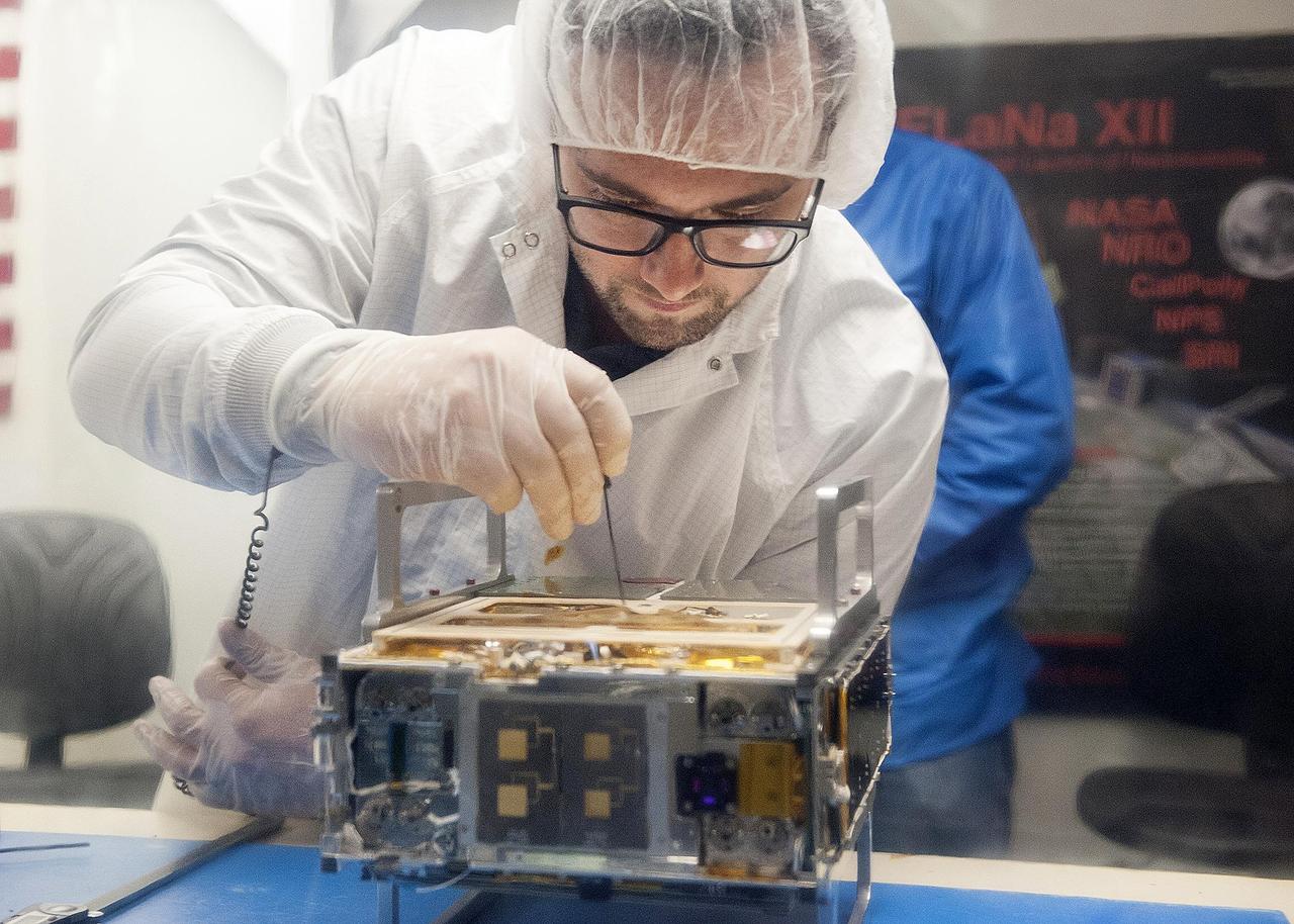 Engineer from JPL making adjustments to a CubeSat.