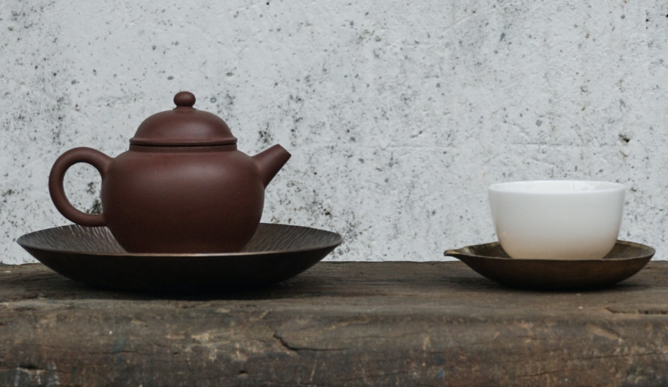 A teapot and cup sitting on a table.
