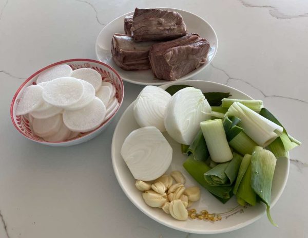 Bowls containing Korean radish, beef, garlic, and leeks.