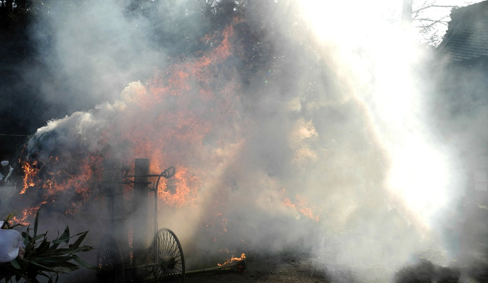 A fire with lots of smoke in front of an ancient building.