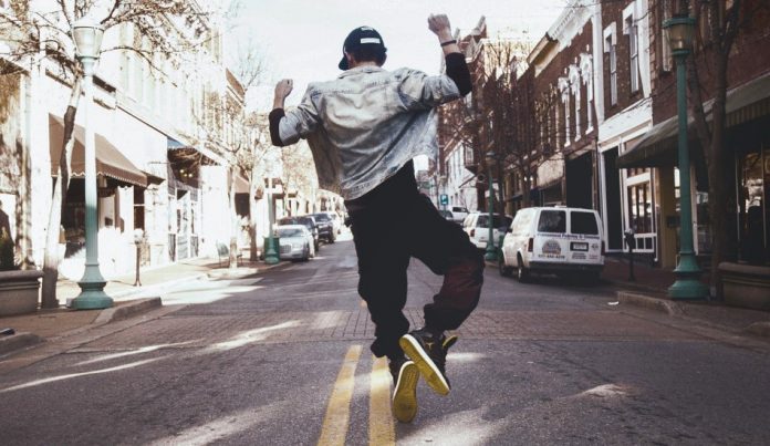 A young man dances in the middle of the street.