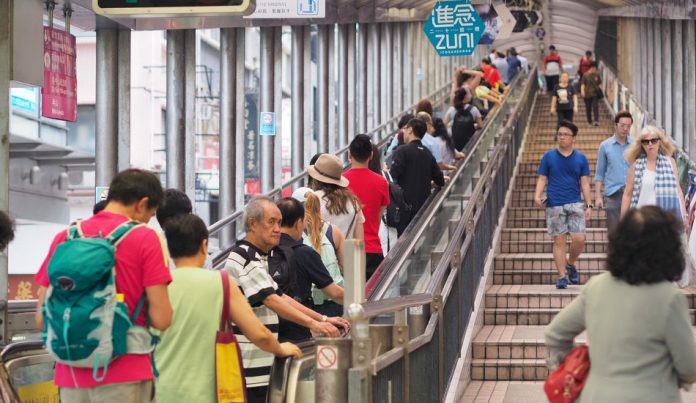 People in Hong Kong riding an escalator on the left and walking down stairs on the right.