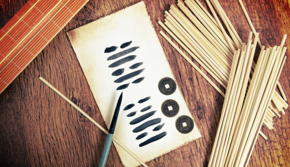 A paper containing trigrams from the Book of Changes lays on a table with a caligraphy brush and divination sticks and coins.