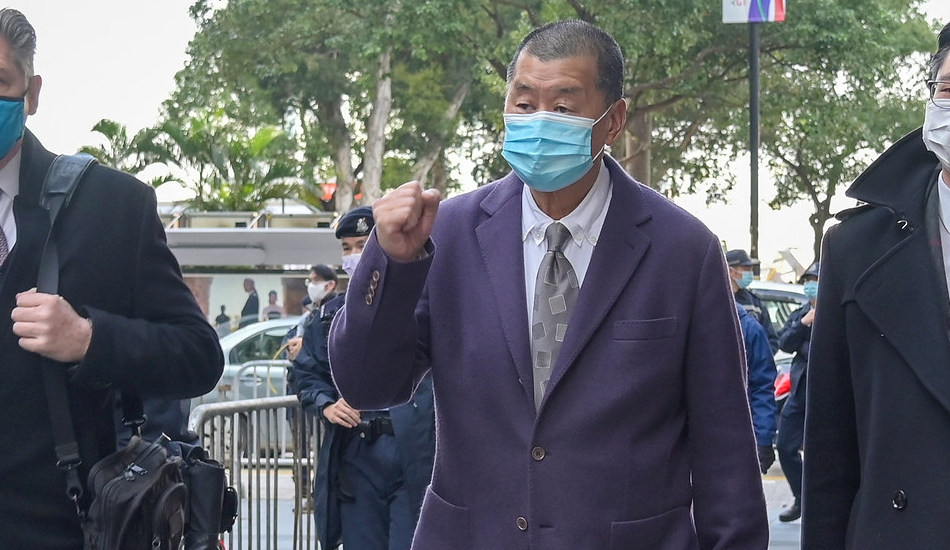 Jimmy Lai walking with fist raised.