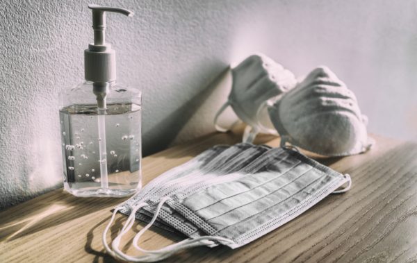 Hand sanitizer sits on a counter along with 2 types of masks.