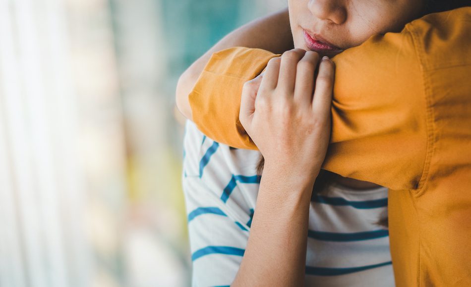 arm in mustard color shirt hugs lady.
