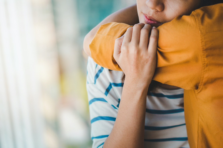 arm in mustard color shirt hugs lady.