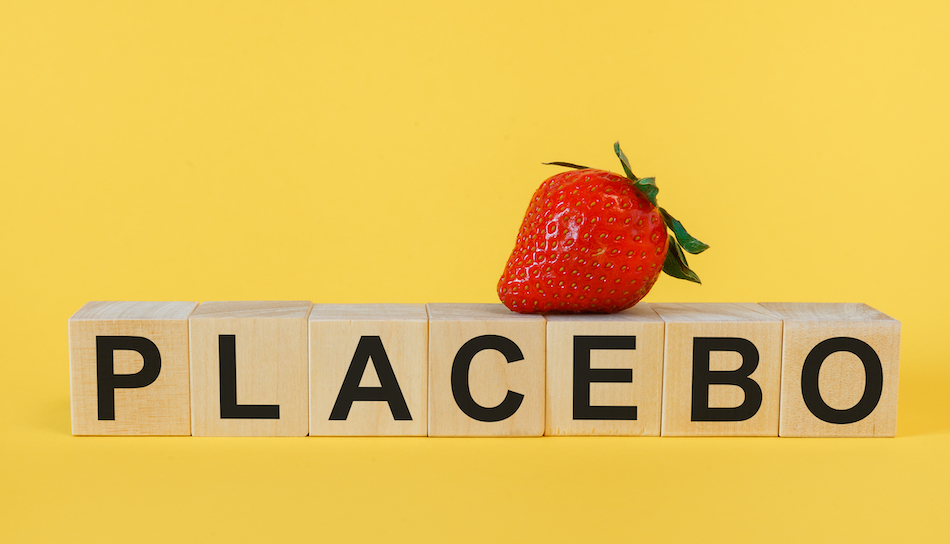placebo spelt out on wooden blocks, yellow background, a strawberry sits on top of some letters.