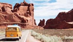A yellow van travels through Arches National Park in Utah.