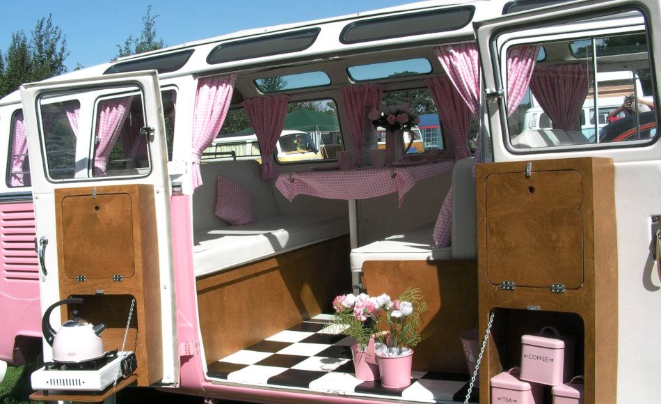 A pink and white campervan with pink and white curtains.