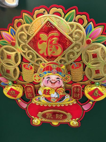 Chinese New Year's Charm. A man standing on a pot of gold. Left and right of him Chinese symbols saying: "wishing you enlarge your wealth."