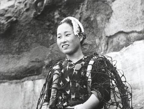 black and white photo of Ama diver holding a barrel and traditional tool and wearing a Tenugi (bandana) in her hair
