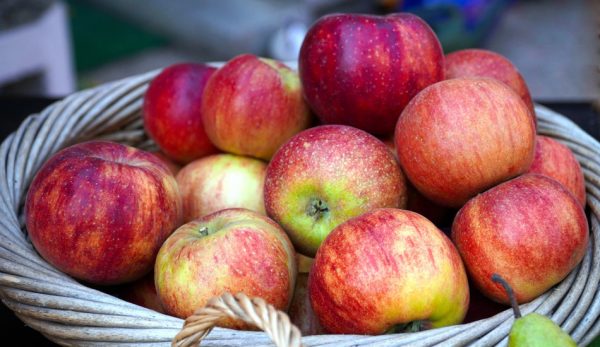 A wicker basket full of ripe red apples.
