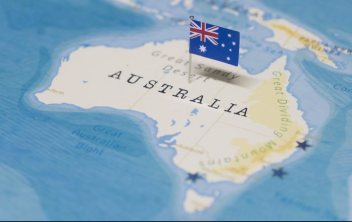 World map with a tiny Australian flag stuck into Australia.