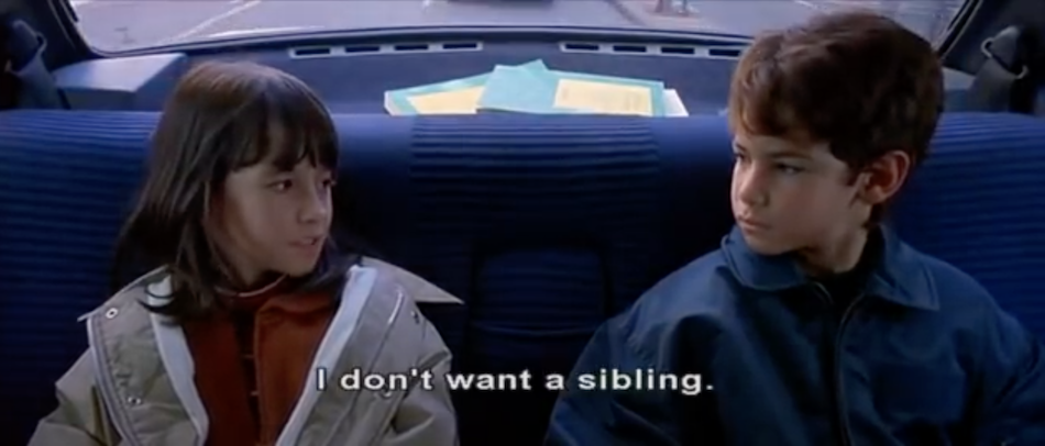two kids in the back of the car look at each other subtitles say 'I don't want a sibling'