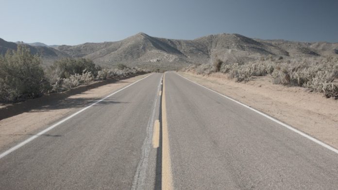 american road with no cars and mountains in background