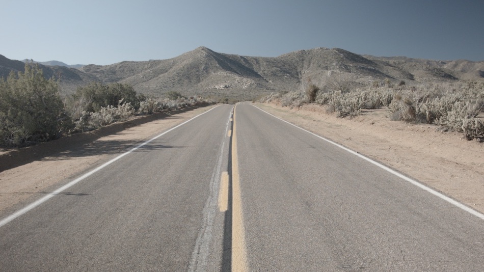 american road with no cars and mountains in background