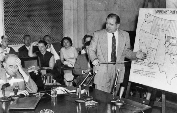 Black and white photo of Senator Joseph McCarthy standing to give a presentation in front of a map of the United States.