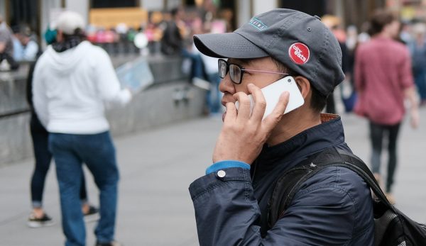 An Asian man talks on his cellphone just outside the Apple store in New York City.