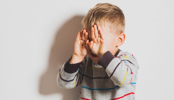 Frustrated little boy crying and covering his face.