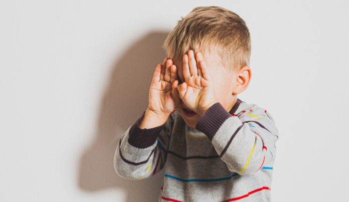 Frustrated little boy crying and covering his face.