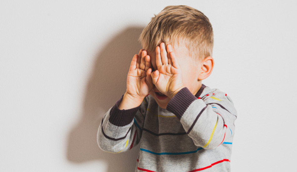 Frustrated little boy crying and covering his face.