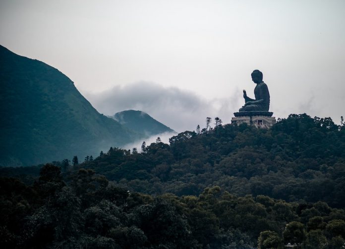 buddha statue on mountain surrounded by clouds