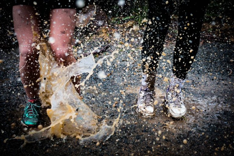 2 people jumping in a puddle water splashes and we only see from knees down