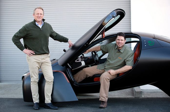 Co-founders of Aptera Motors, Steve Fambro and Chris Anthony, with a black Aptera 3-wheeled Electric Vehicle.