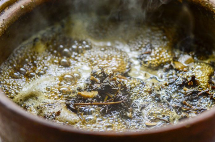 Closeup of boiling Chinese herbal medicine soup in a clay pot.