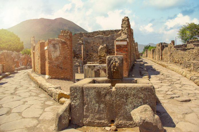Ancient water well in Pompeii with Mount Vesuvius in the background.