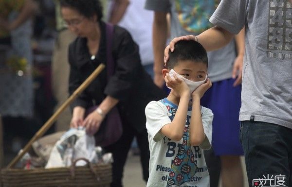 Boy covers face from smoke at Qingming festival.